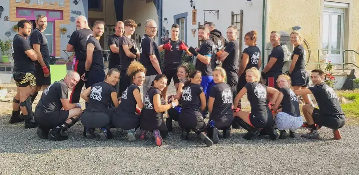 Une vingtaine de boxeuses et boxeurs du TCMS, debout et accroupis, montrent fièrement le logo du club imprimé dans le dos de leur t-shirt.